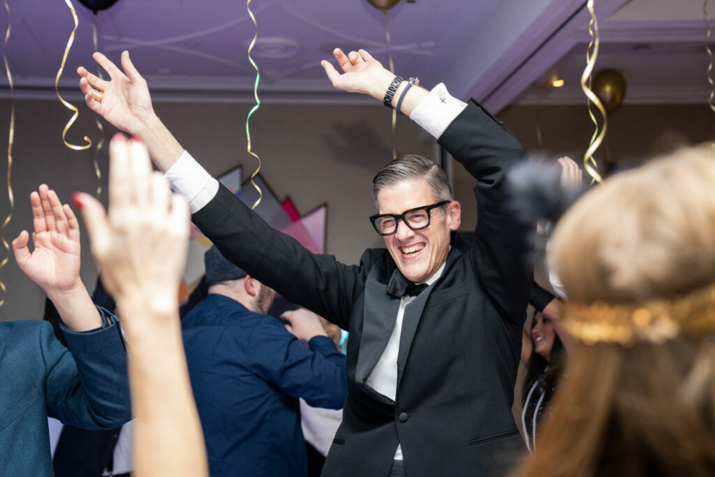 Sholto Smith dances at a party wearing a tuxedo