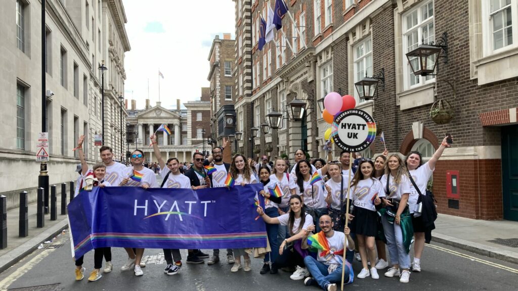 Hyatt colleagues holding a Hyatt banner stand outside a Hyatt hotel celebrating Pride