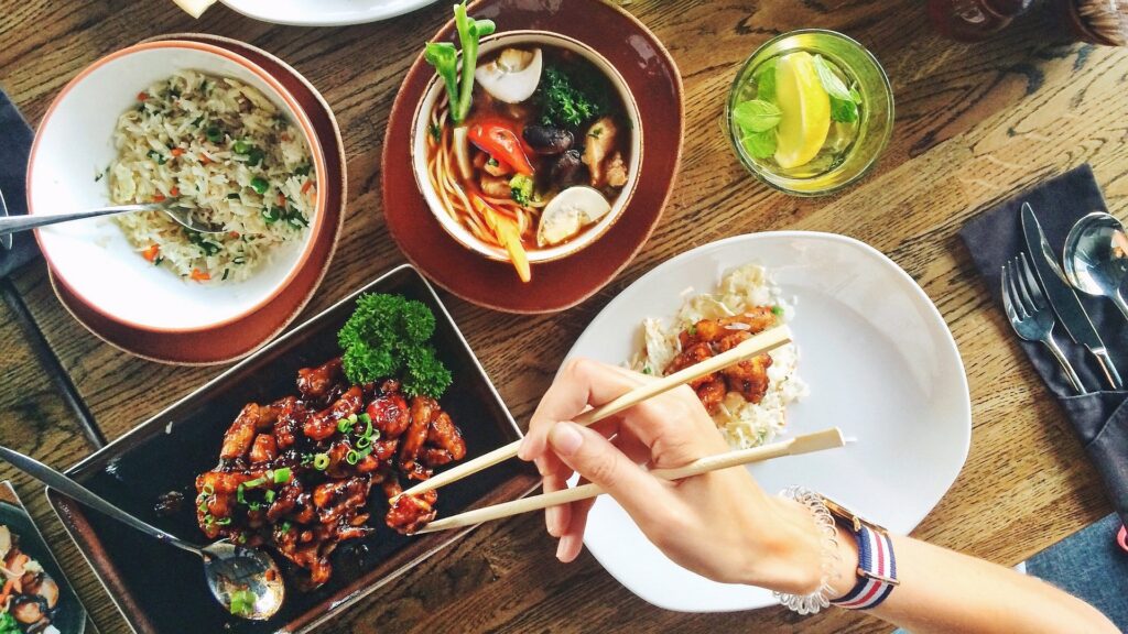 A person holding chopsticks beating a takeaway