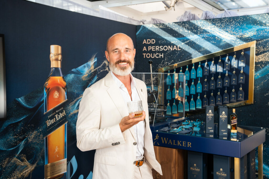 A man stands in front of a display of whisky bottles