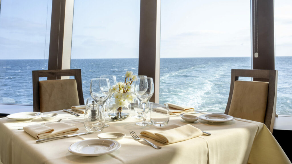 A dining table for two by a window on a cruise ship