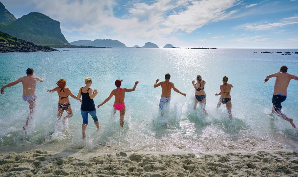 Group of people running into the ocean playfully