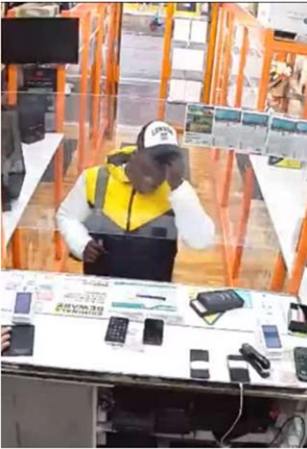 CCTV still of a man in front of a desk in a shop