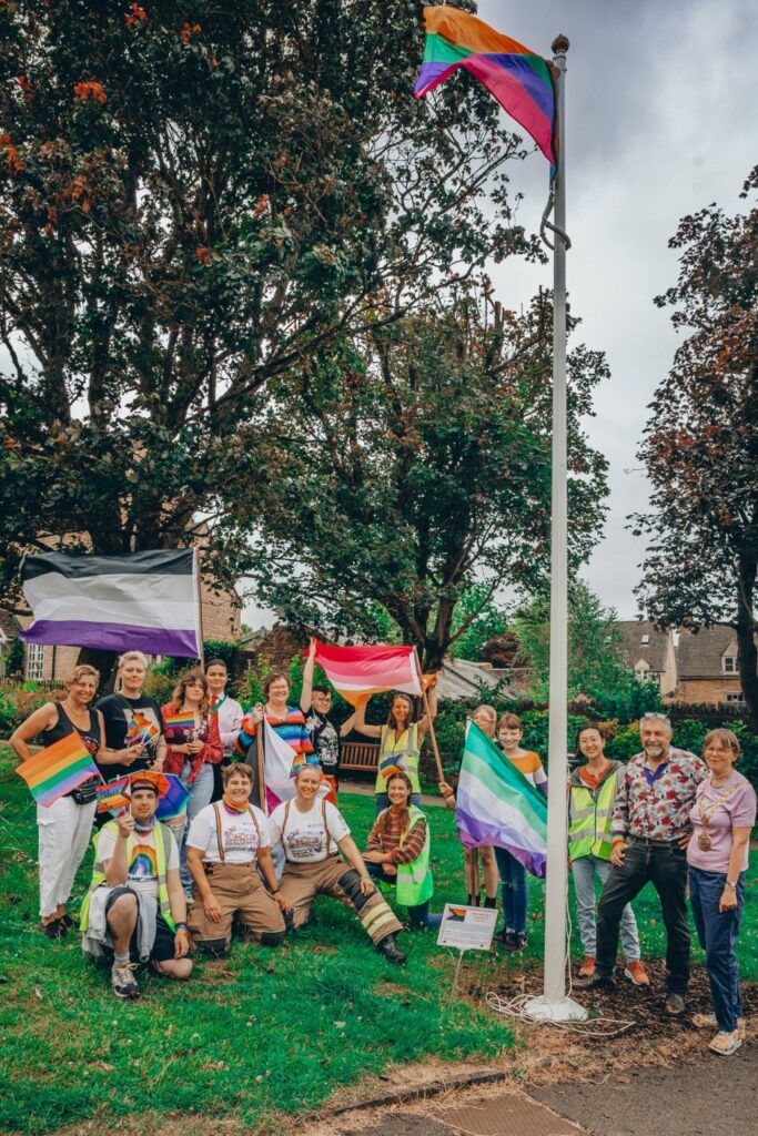 Group of people on a village green flying Pride flags