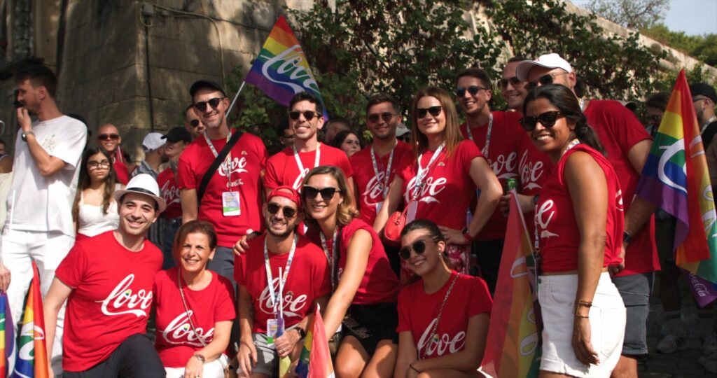 Group of smiling people in Coca-Cola T-shirts at a Pride event