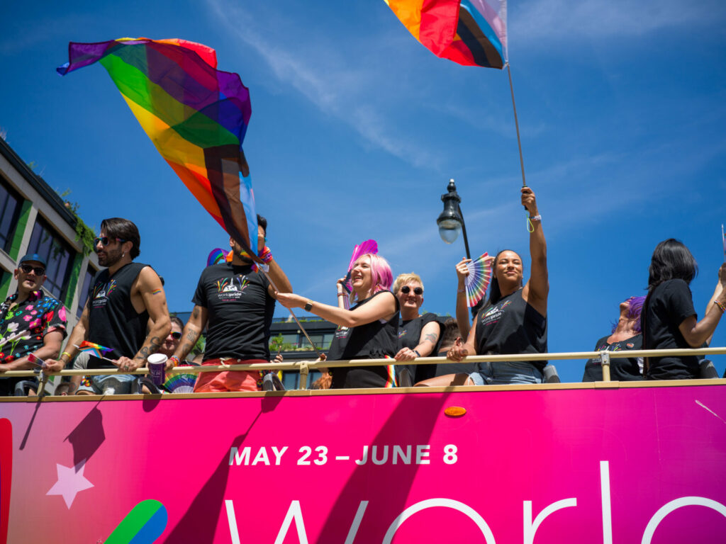 People celebrating Pride on a pink bus