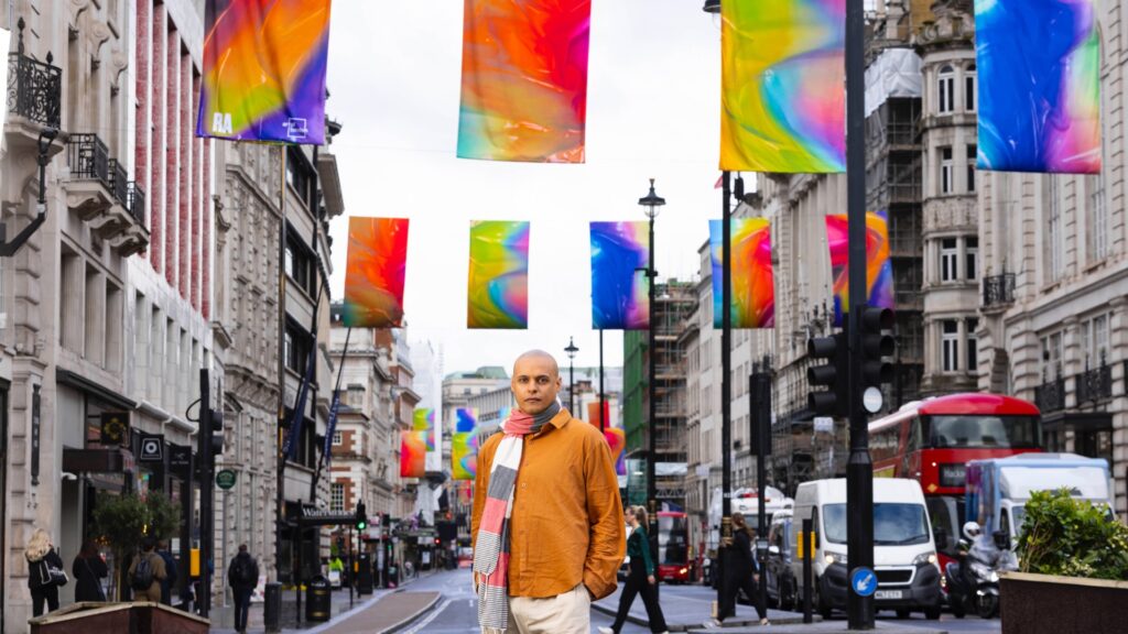 One of the artists standing n the street beneath the flags