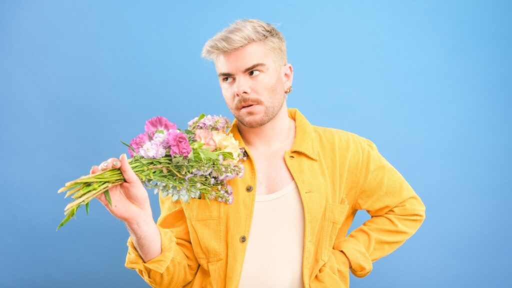 Christopher Hall in a yellow shirt holding flowers