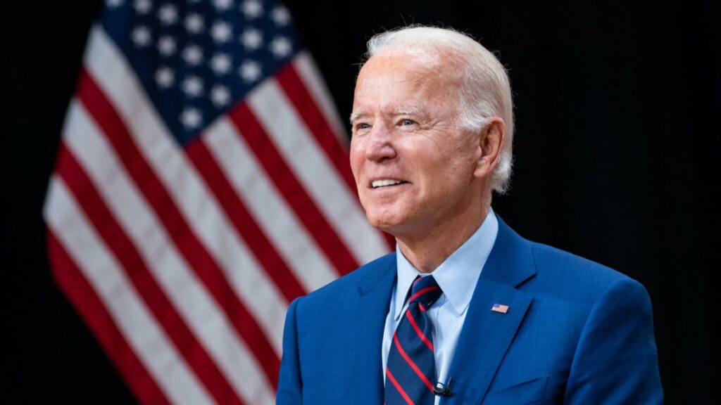 A portrait of Joe Biden with a US flag in the background