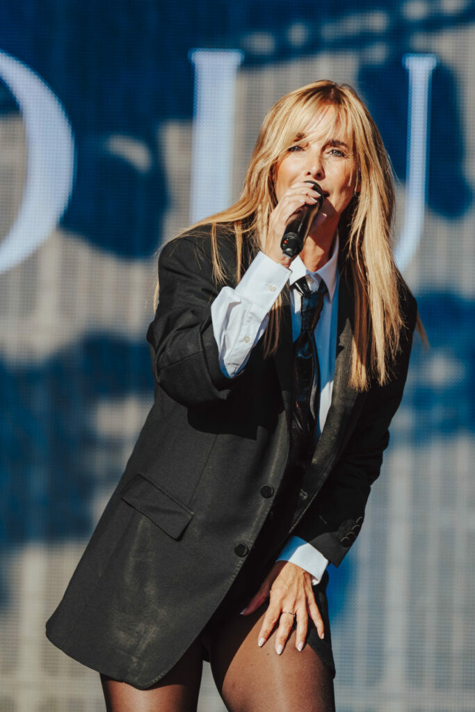 Louise singing in a shirt, tie and blazer
