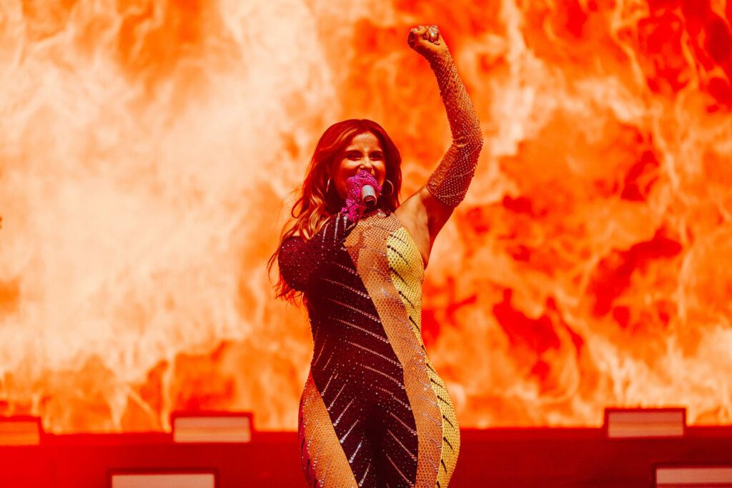 Nelly Furtado in a leotard against a fire background