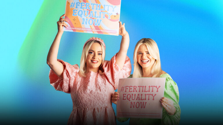 Two women holding up signs saying Fertility Equality now