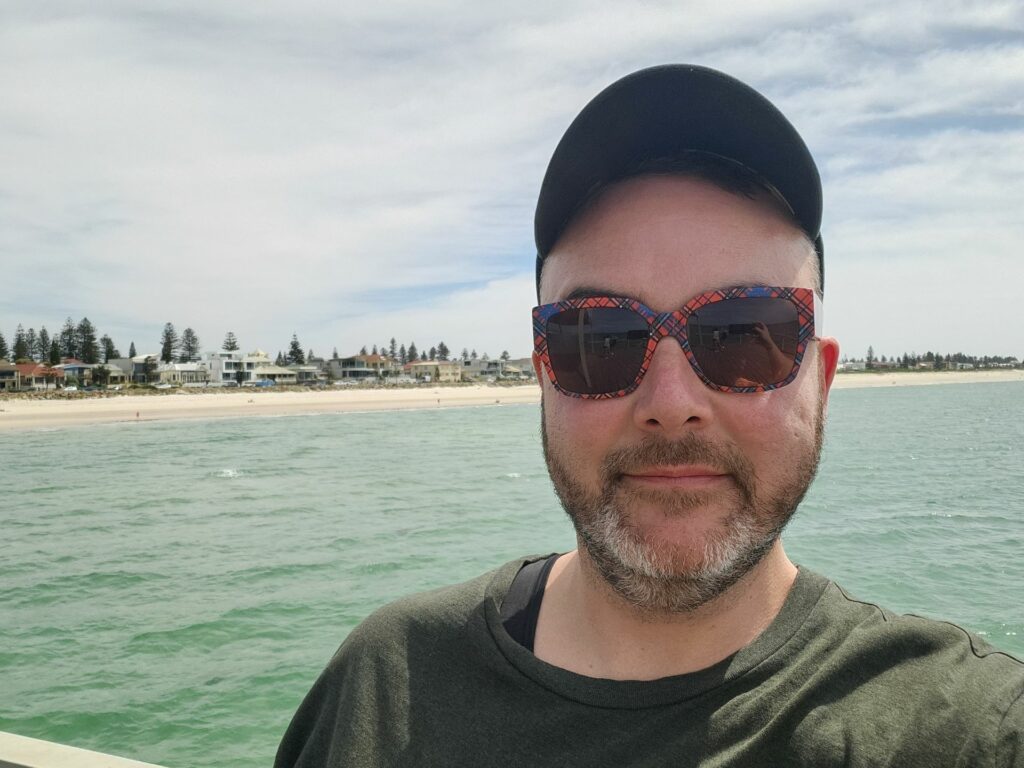 A smiling person takes a selfie at Henley Beach