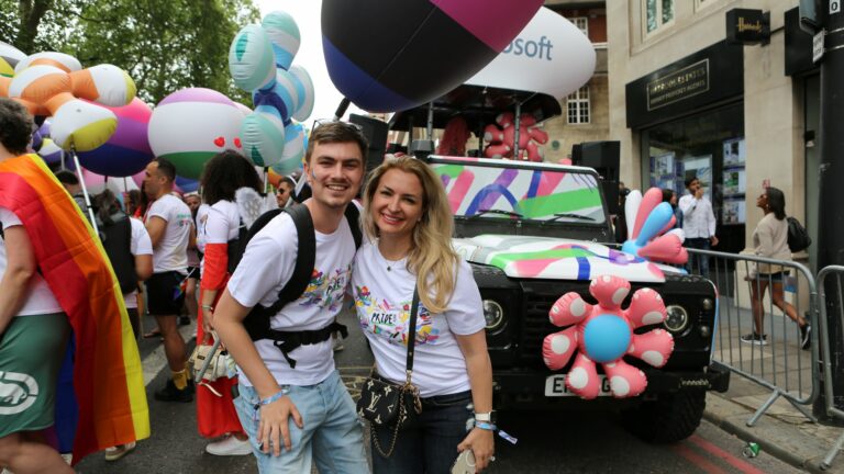 A smiling man and woman in a Pride parade