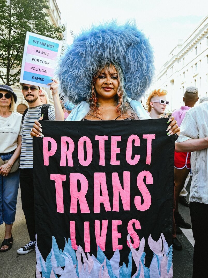 An attendee holding a sign saying 'Protect Trans Lives'