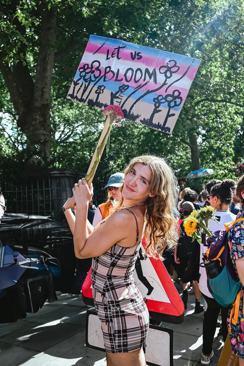 someone holding a sign saying 'let us bloom'