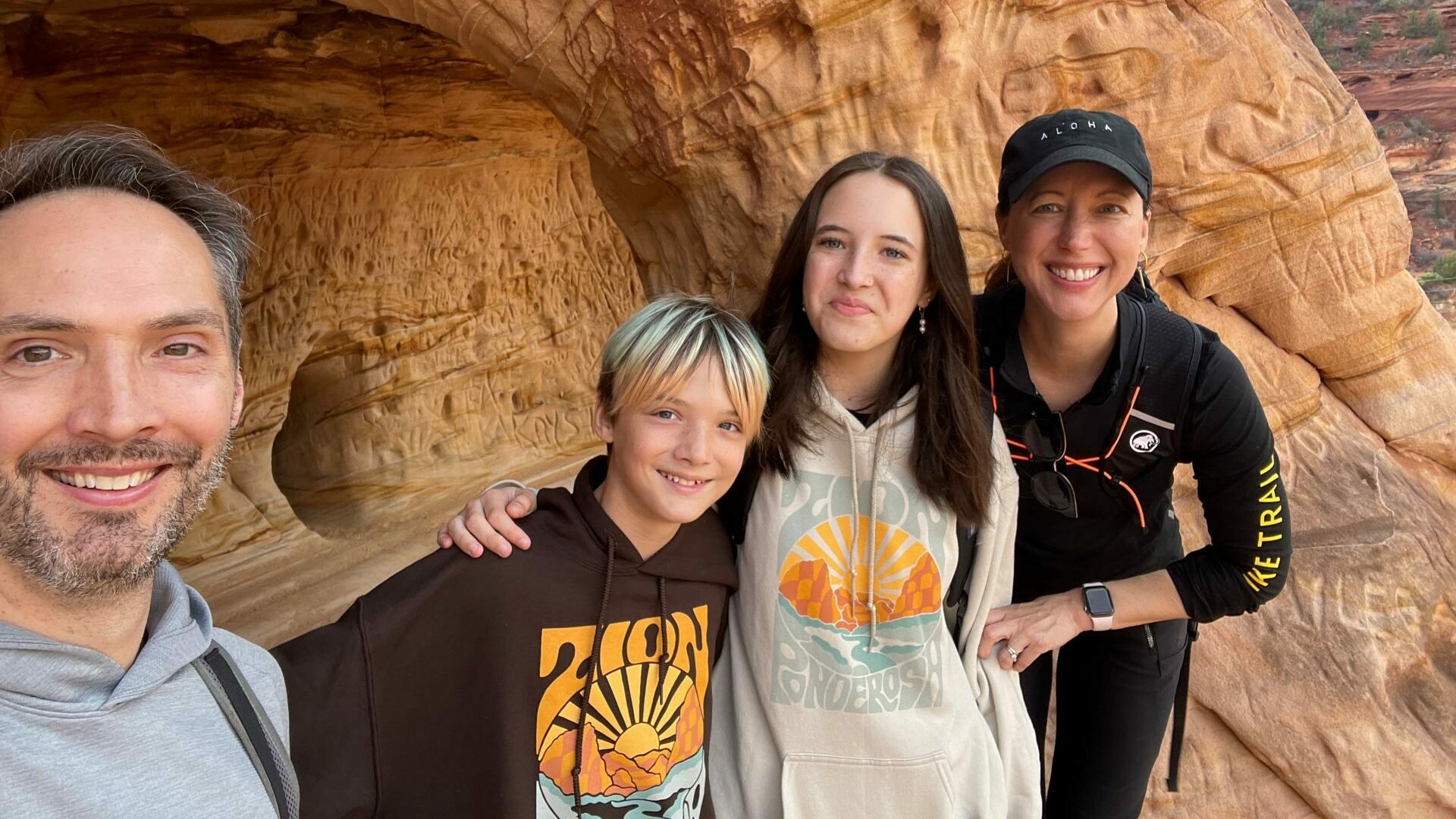 A family hug in front of a sandy rock