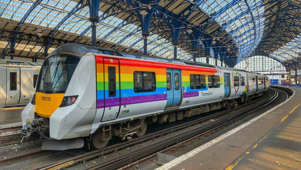 A train with Pride coloured decal sits in a train station