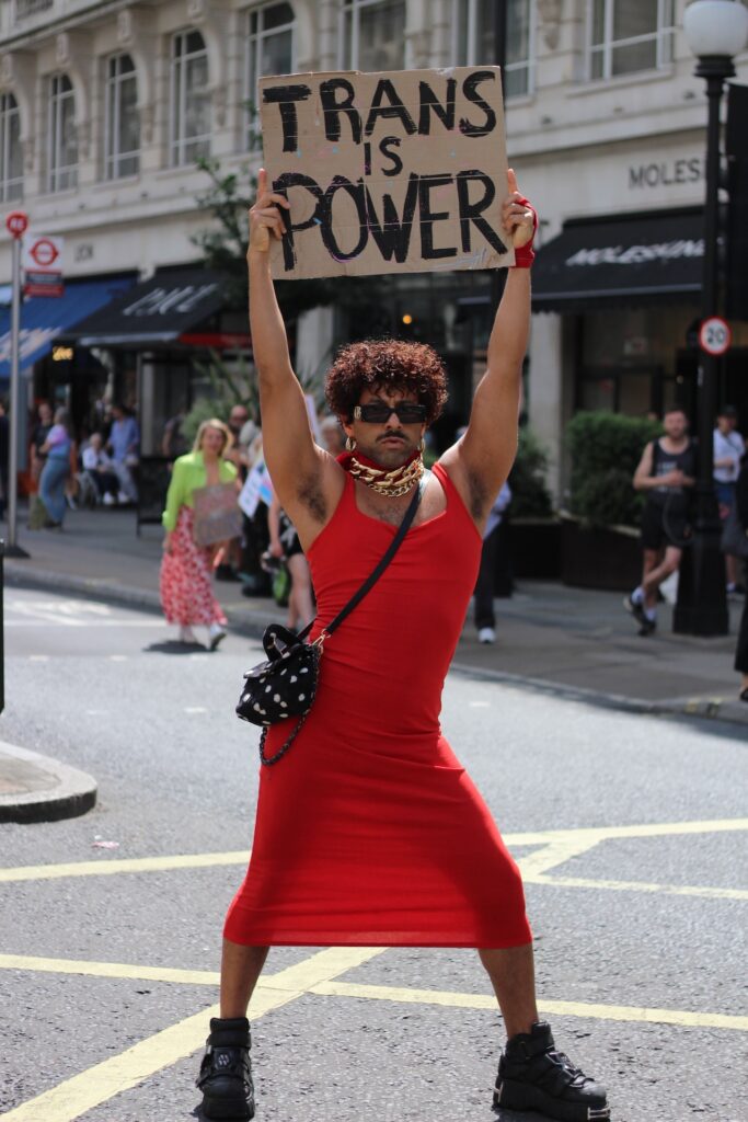 An attendee is a red dress holding a sign saying 'trans is power'