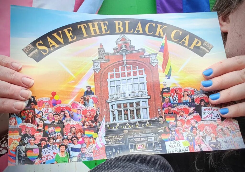 A person holding an image of the Black Cap with campaigners around it