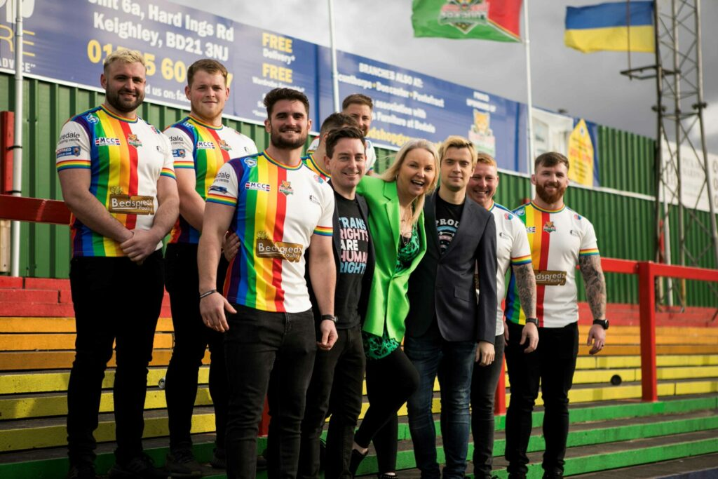 Rugby players in rainbow kits stand with the club's owners and India Willoughby