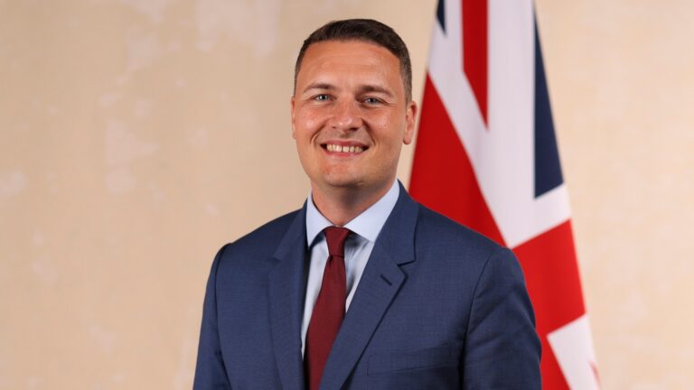 Wes Streeting standing in front of a Union Jack gflag