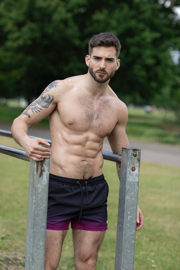 Vince topless against a tree and grass background