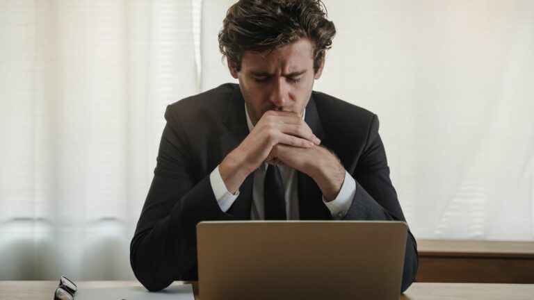Stock image of man sitting in front of a laptop looking sad