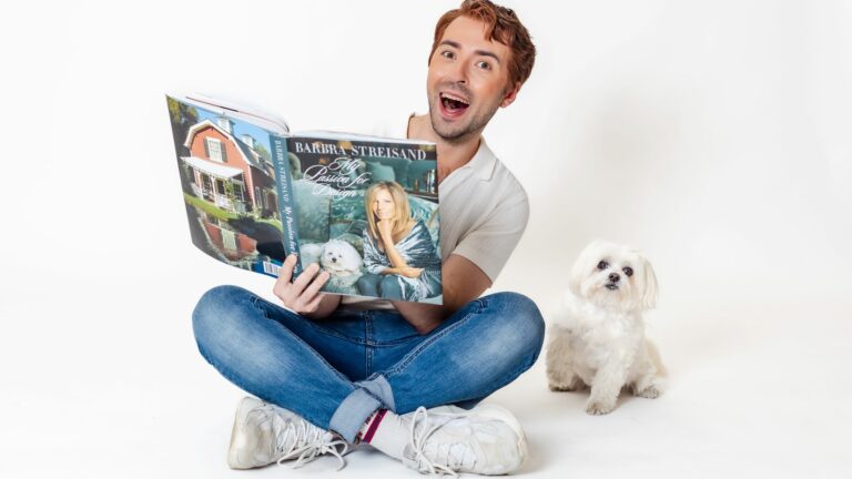 Rob Madge sitting down with a book with a white dog