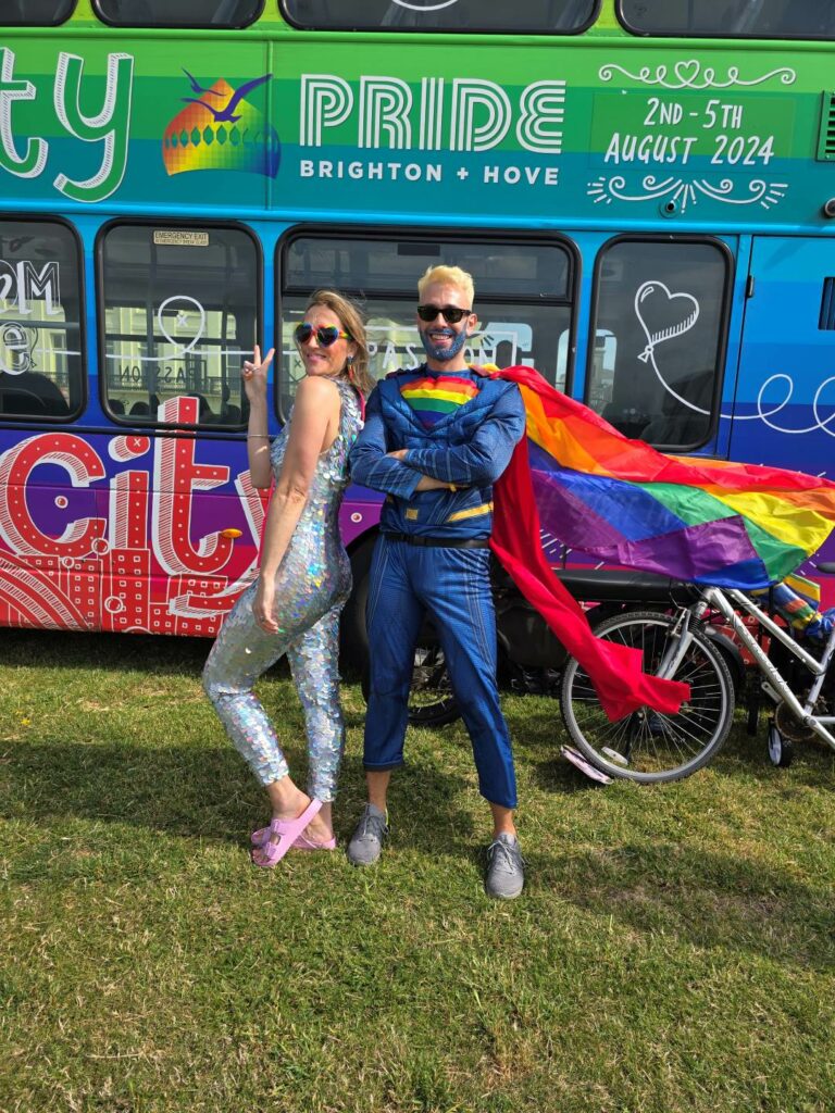 Two people in costumes standing in front of a Pride bus