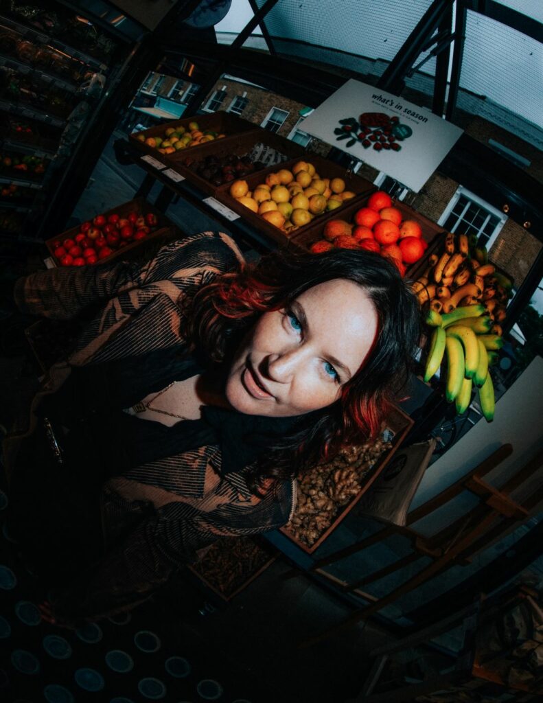 A woman against a backdrop of fruit and vegetables