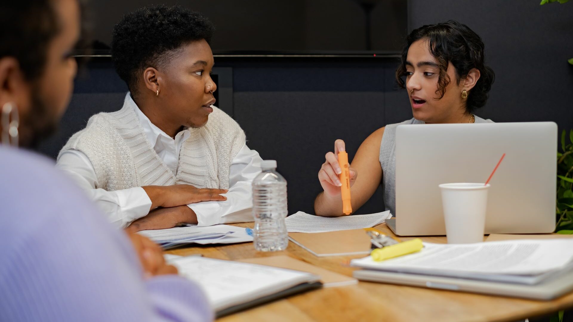 A trans person and a trans man discussing something in a meeting