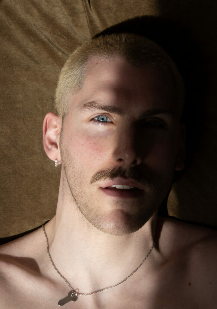 a close up of a person's face, with a chain around their neck