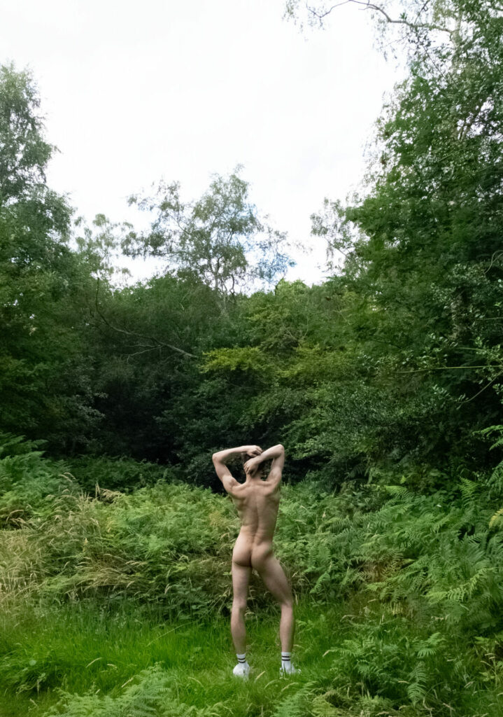 a nude person shot from behind facing foliage 