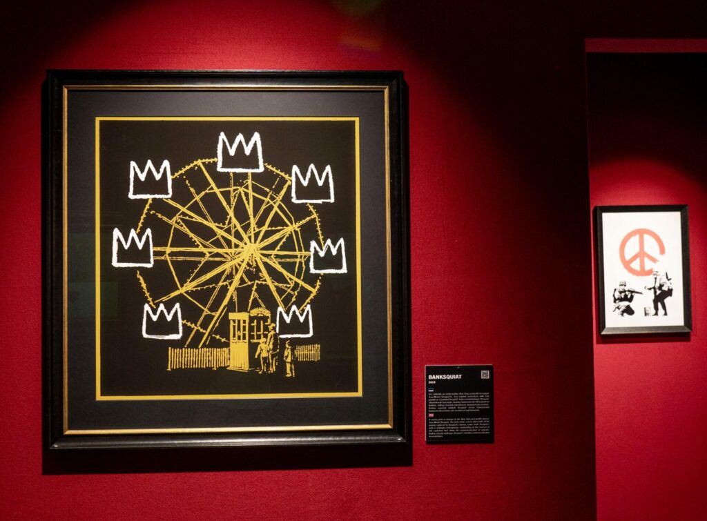 A Banksy painting of a ferris wheel with Basquiat crowns as the cars