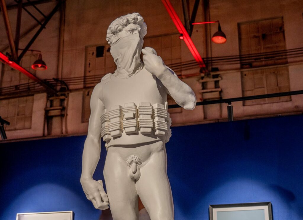 A Banksy sculpture of a naked statue wearing a mask with bombs strapped to him