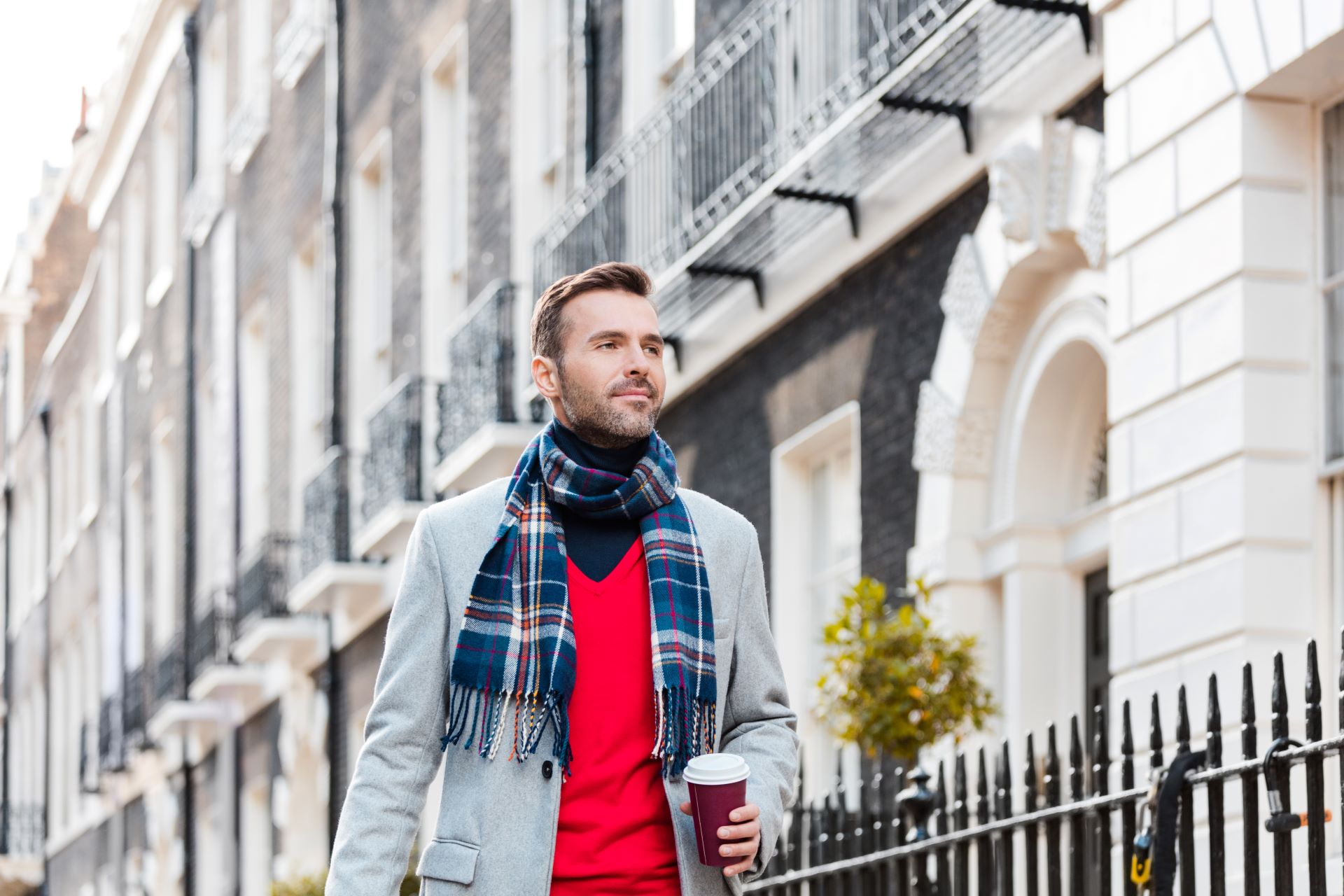 A man walking through London wearing a red scarf