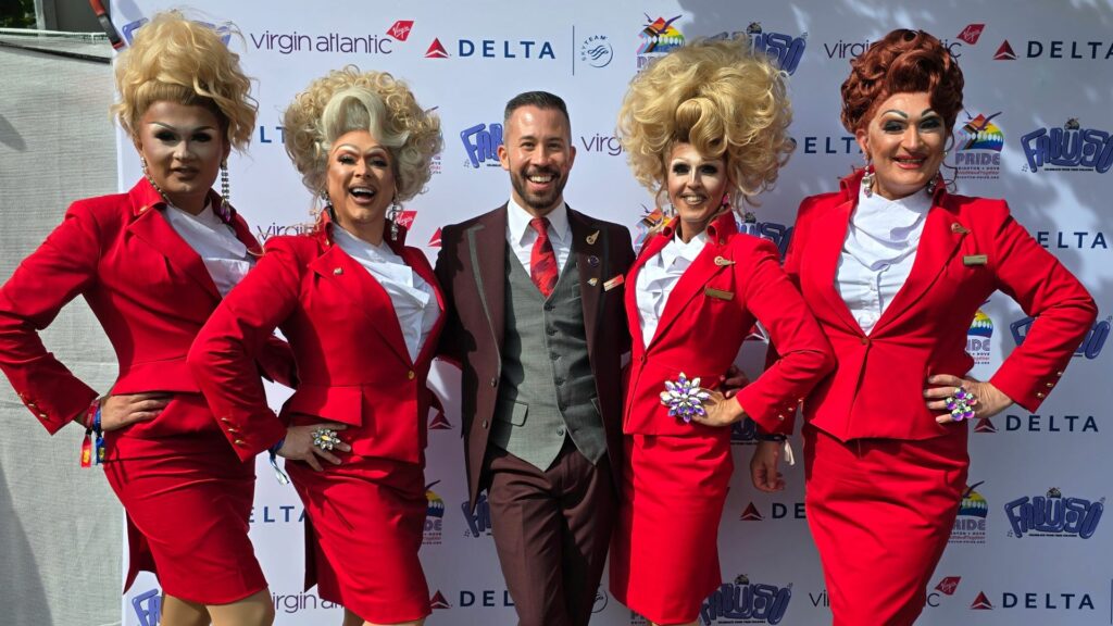 Drag queens in Virgin Atlantic outfits with a male flight attendant in the centre