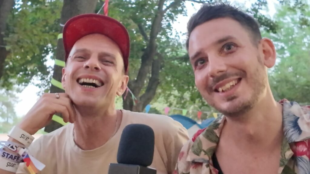 Two smiling men holding a mic