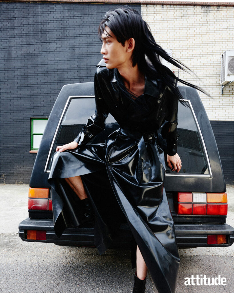 Model leans against car wearing a latex leather coat by Atsuko Kudo and leather boots by Christian Louboutin