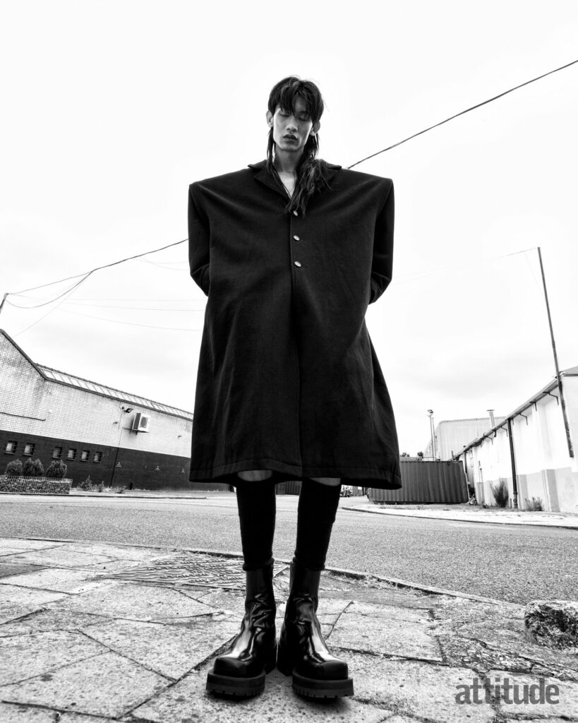 Model wears oversized, boxy overcoat by Edward Brutchley and knee high leather boots by Diesel