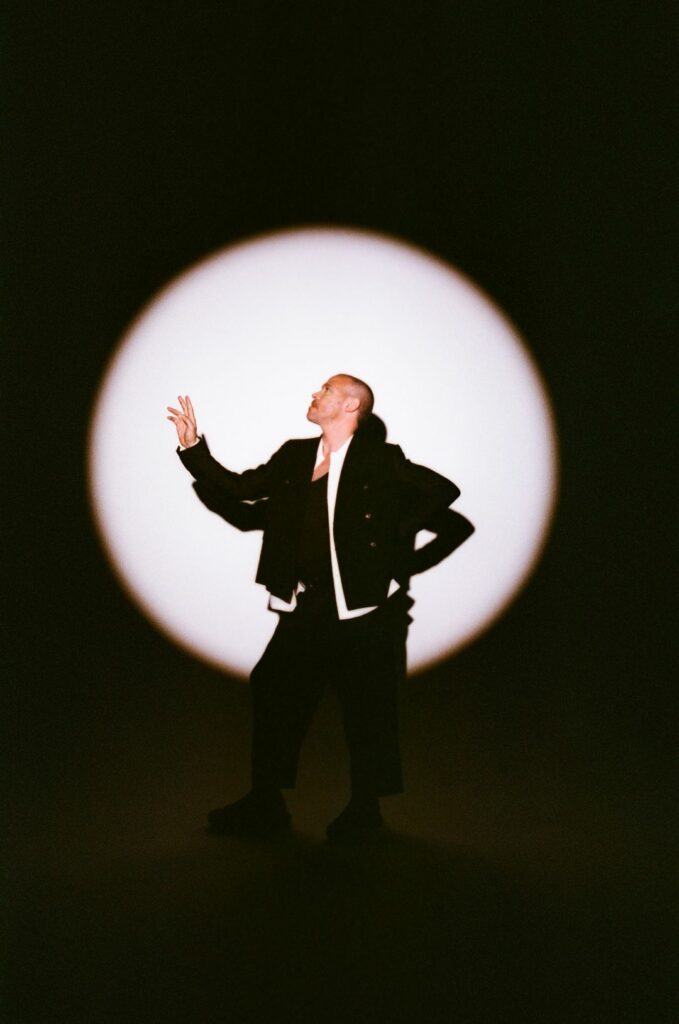 Will Young standing in front of a spotlight backdrop