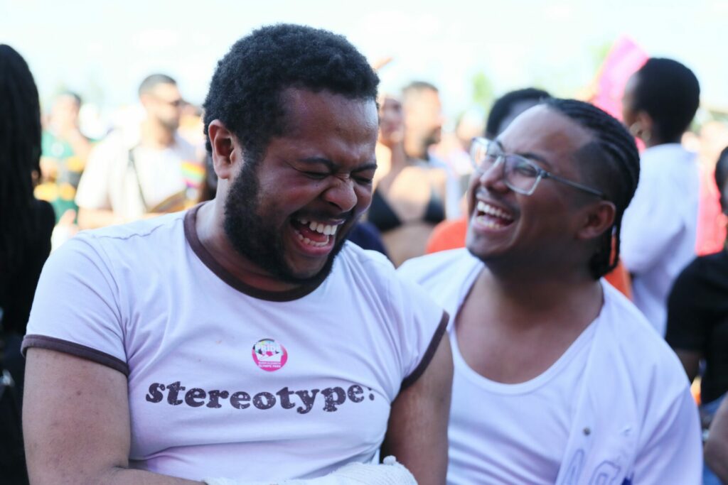 two uk black pride attendees in white share a joke