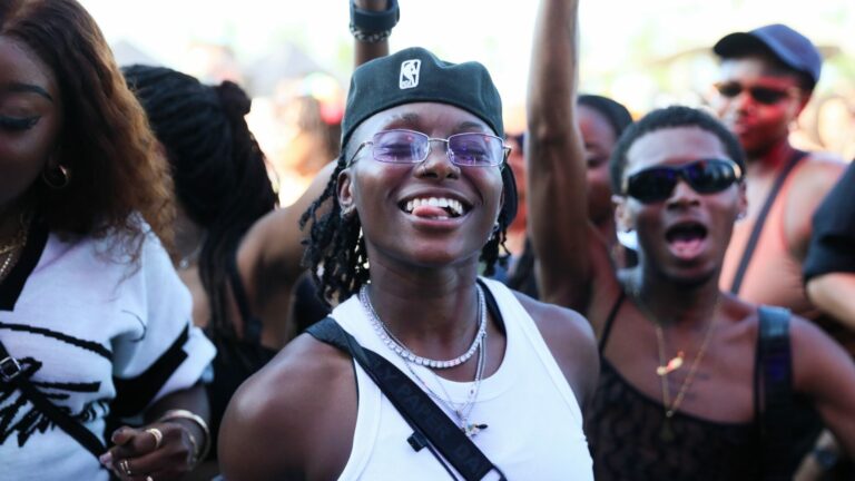 An attendee in a white vest with tongue sticking out