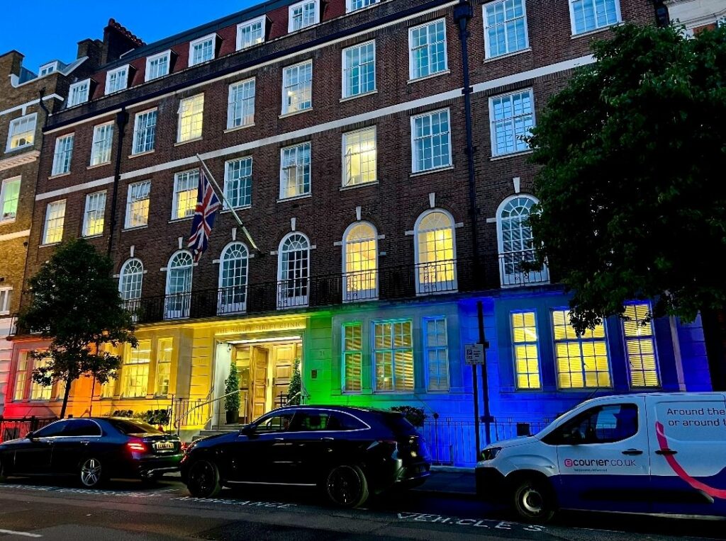 External shot of an office at night covered in Pride coloured light