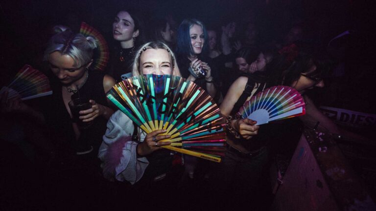 A person in a nightclub holding a fan