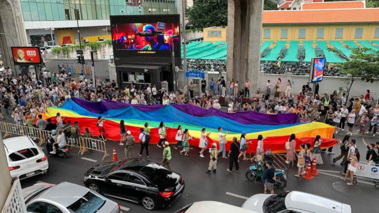 A picture of a rainbow flag being carried by activists during Bangkok Pride