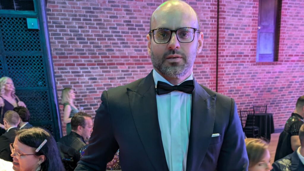 A man in a dinner jacket and glasses