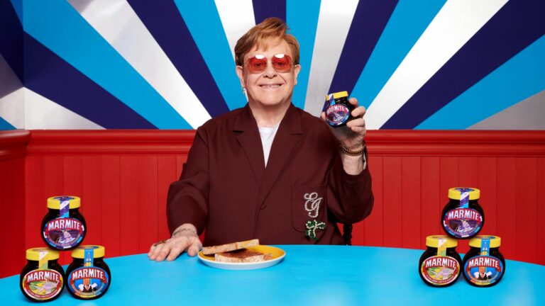 Elton John holding a jar of Marmite