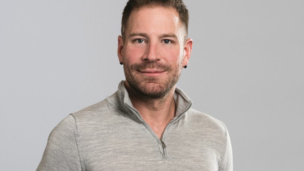 A smiling man in a grey top